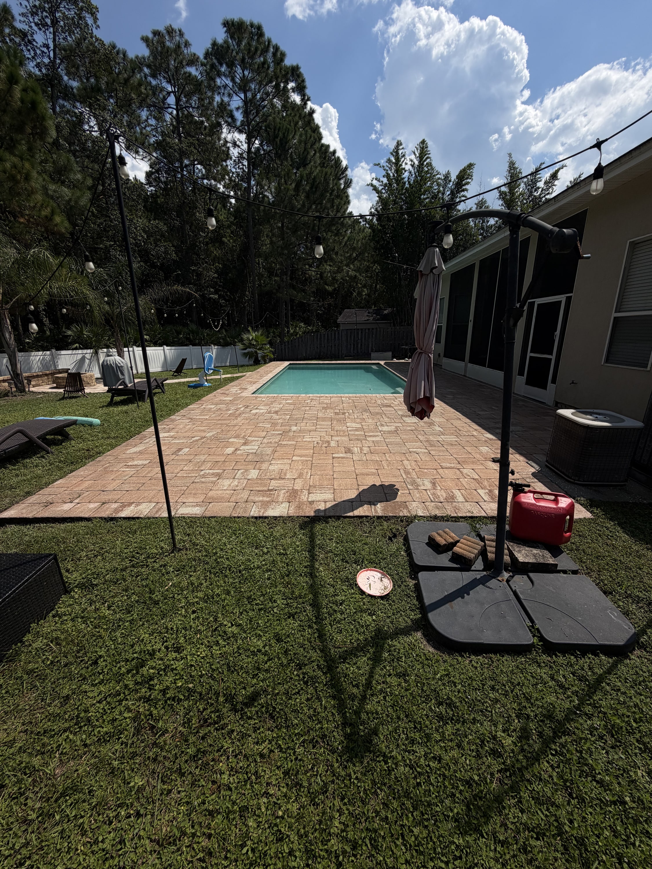 Brick paver patio and pool surround in completed backyard landscape.