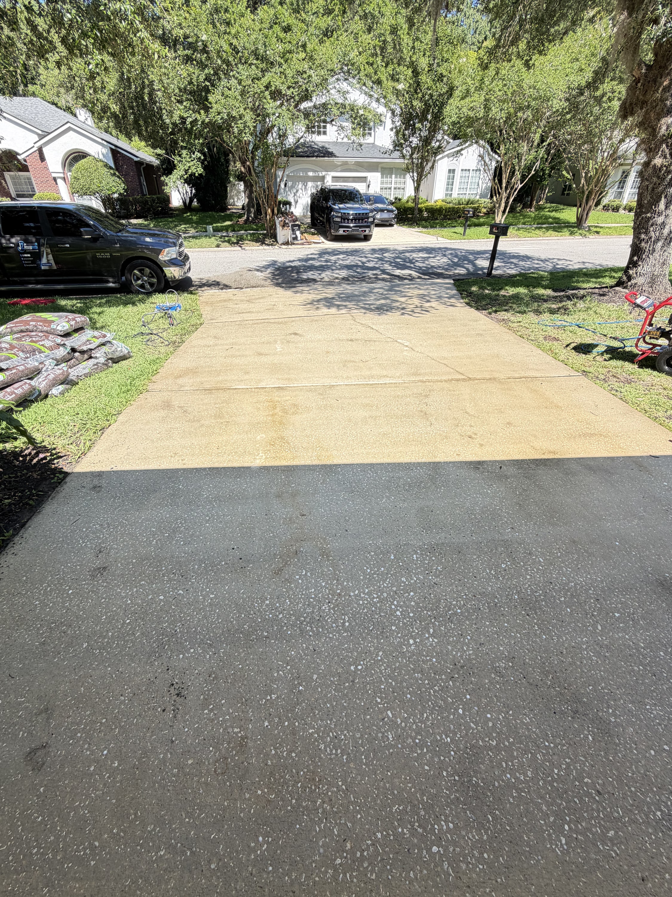 Driveway being pressure washed, half cleaned and half dirty, showing the before and after.