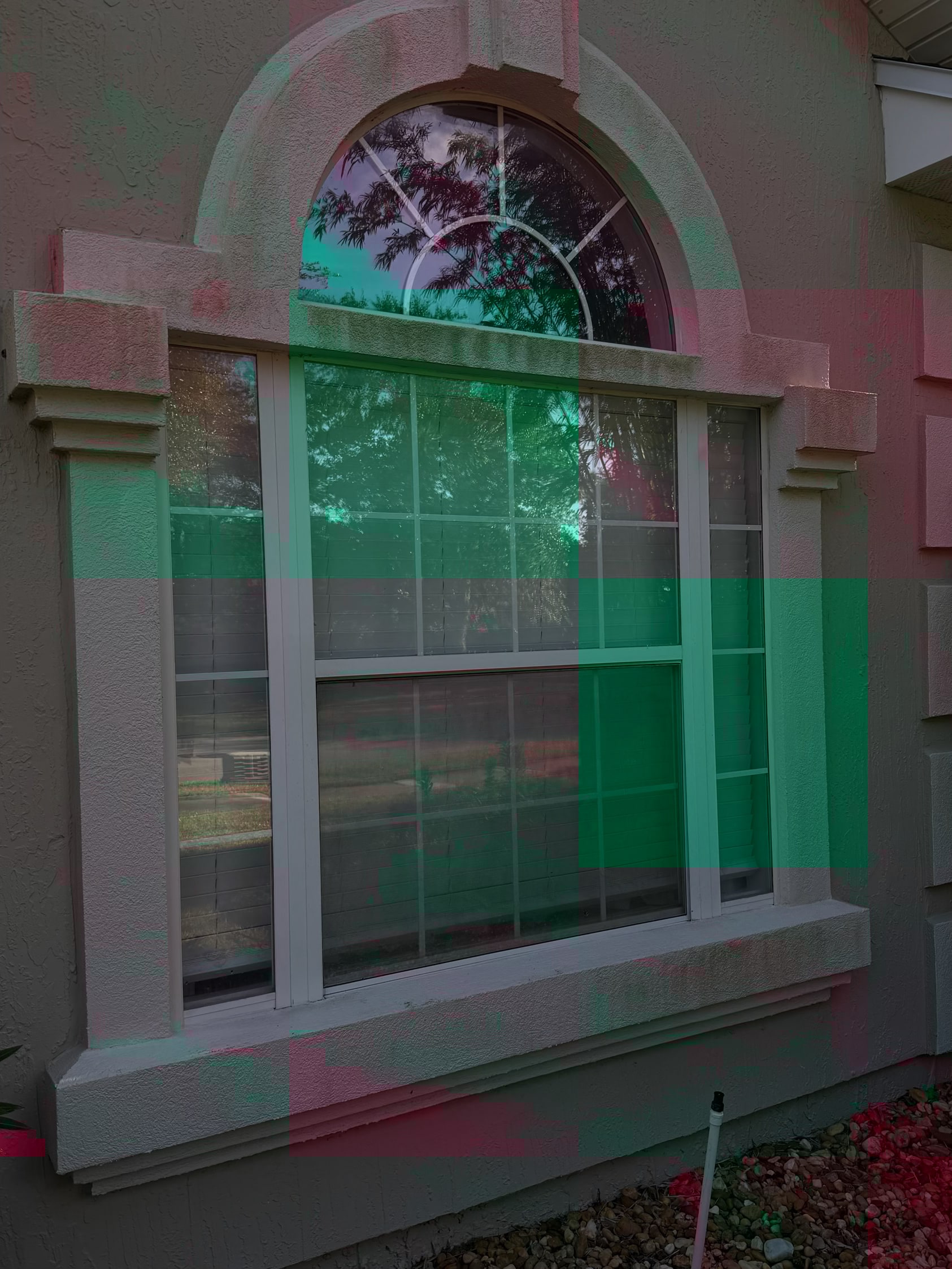 Cleaned sash window with arched top and white frame on pink and green rendered wall