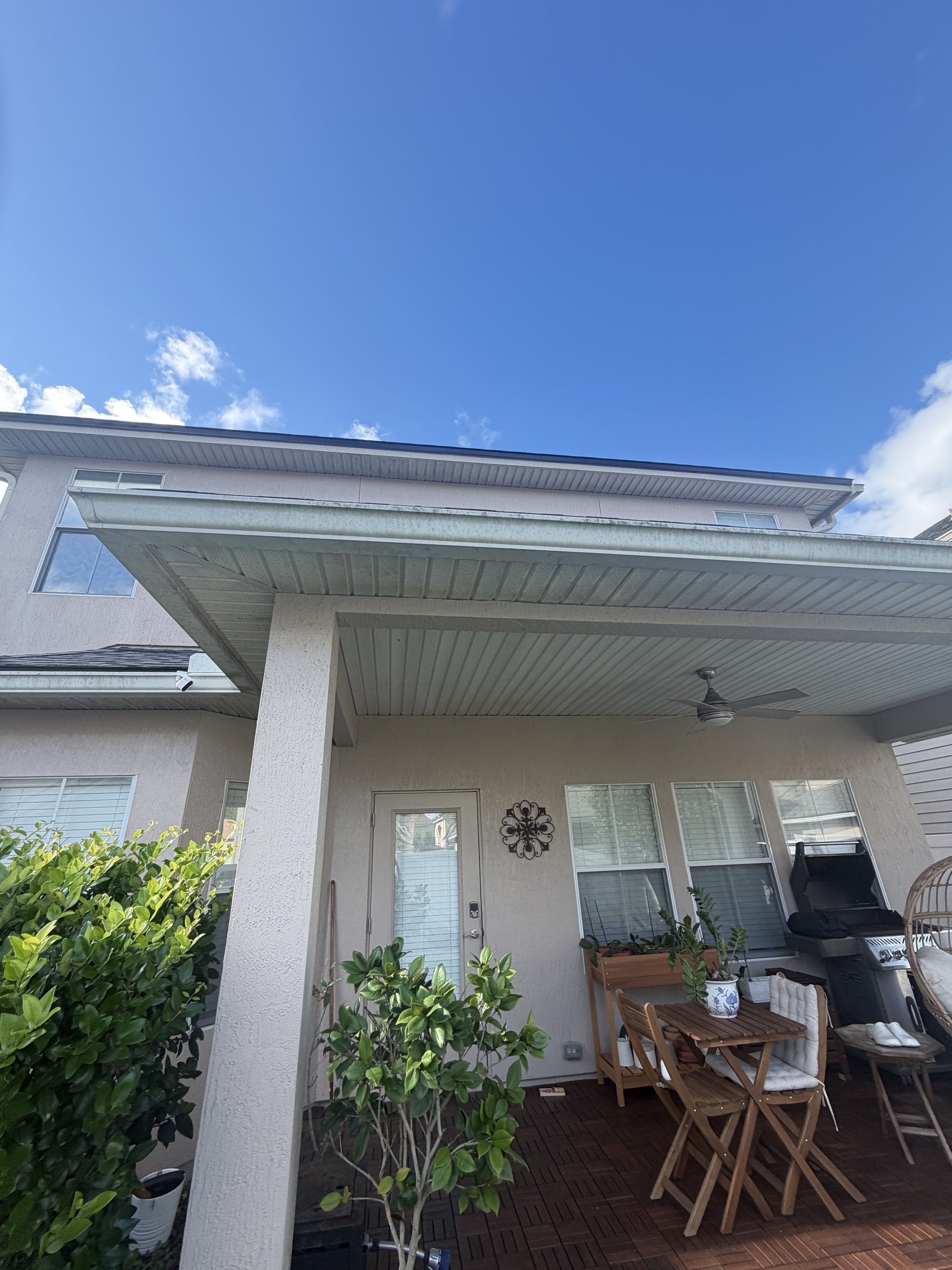 Metal patio cover with corrugated roof panels over composite decking and seating area