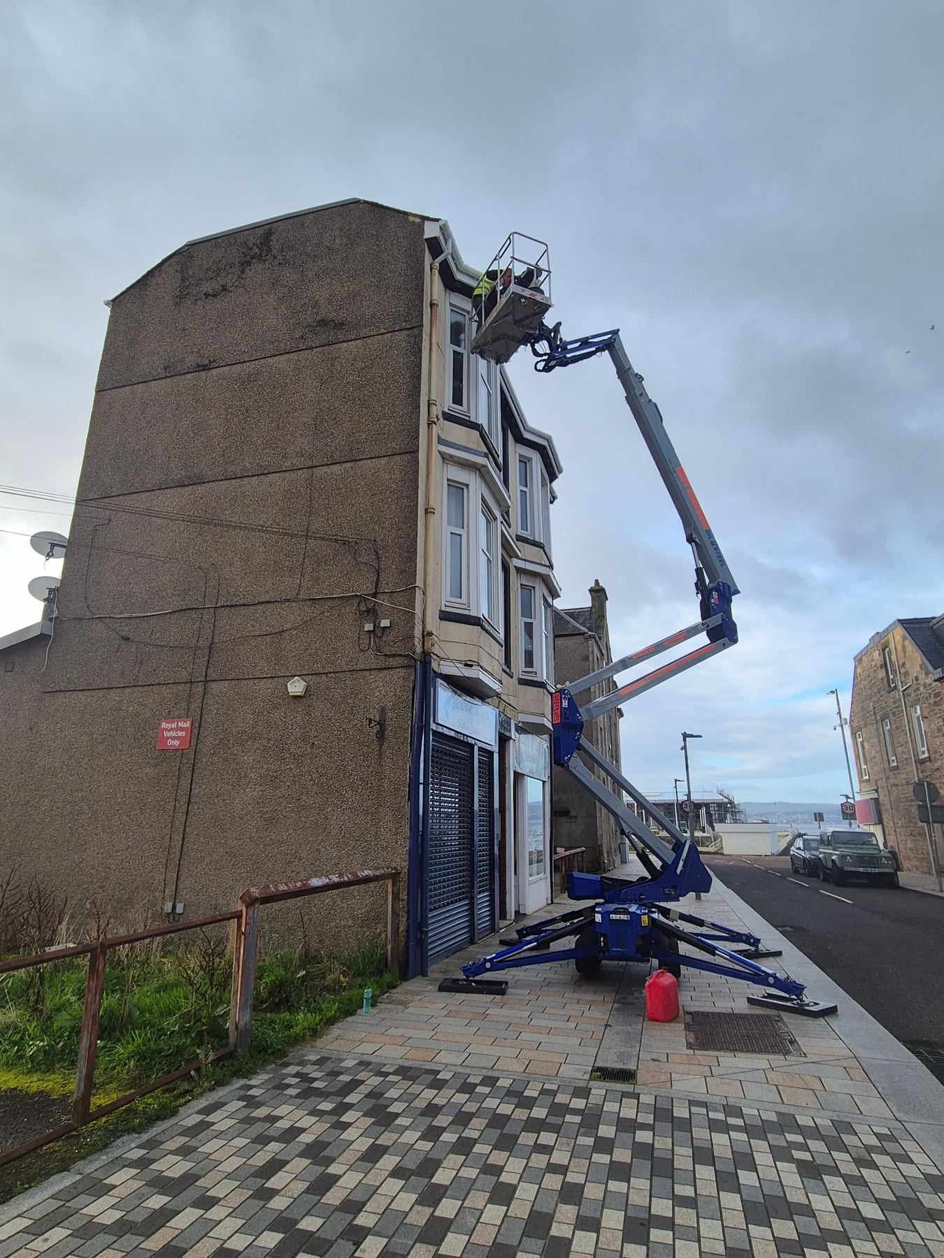 Mobile elevated work platform against brown stone tenement building for high-level facade work.