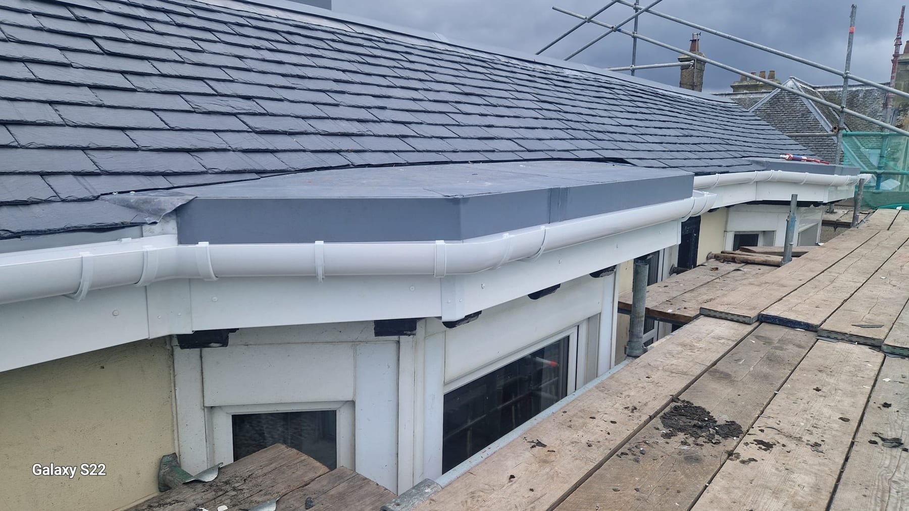 Newly installed slate roof with white uPVC gutters and downpipes on a house